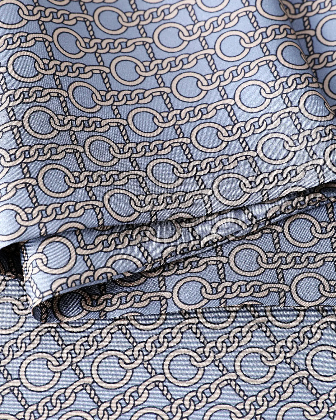 Close-up detail of grey blue paisley pattern on 100% mulberry silk scarf for men.#color_dove-gray