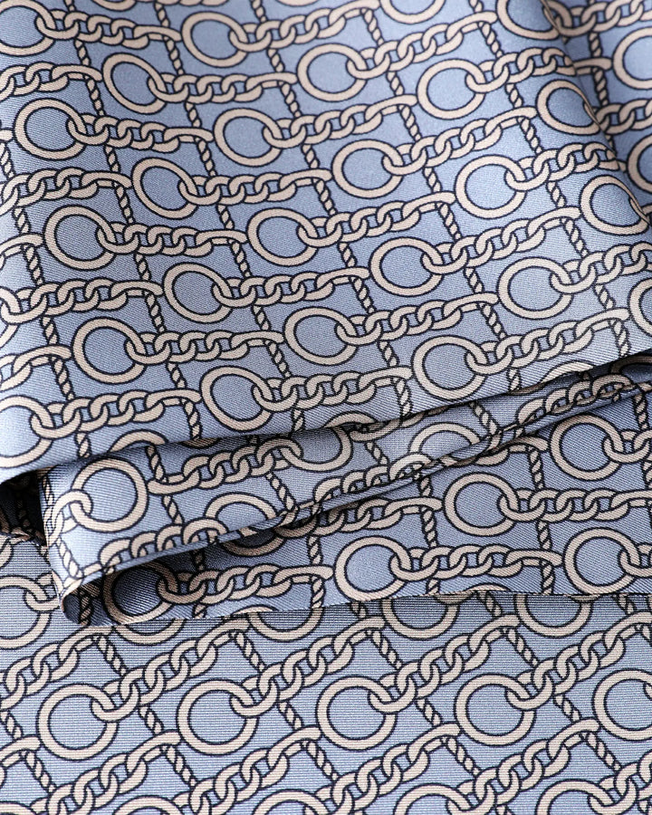 Close-up detail of grey blue paisley pattern on 100% mulberry silk scarf for men.#color_dove-gray
