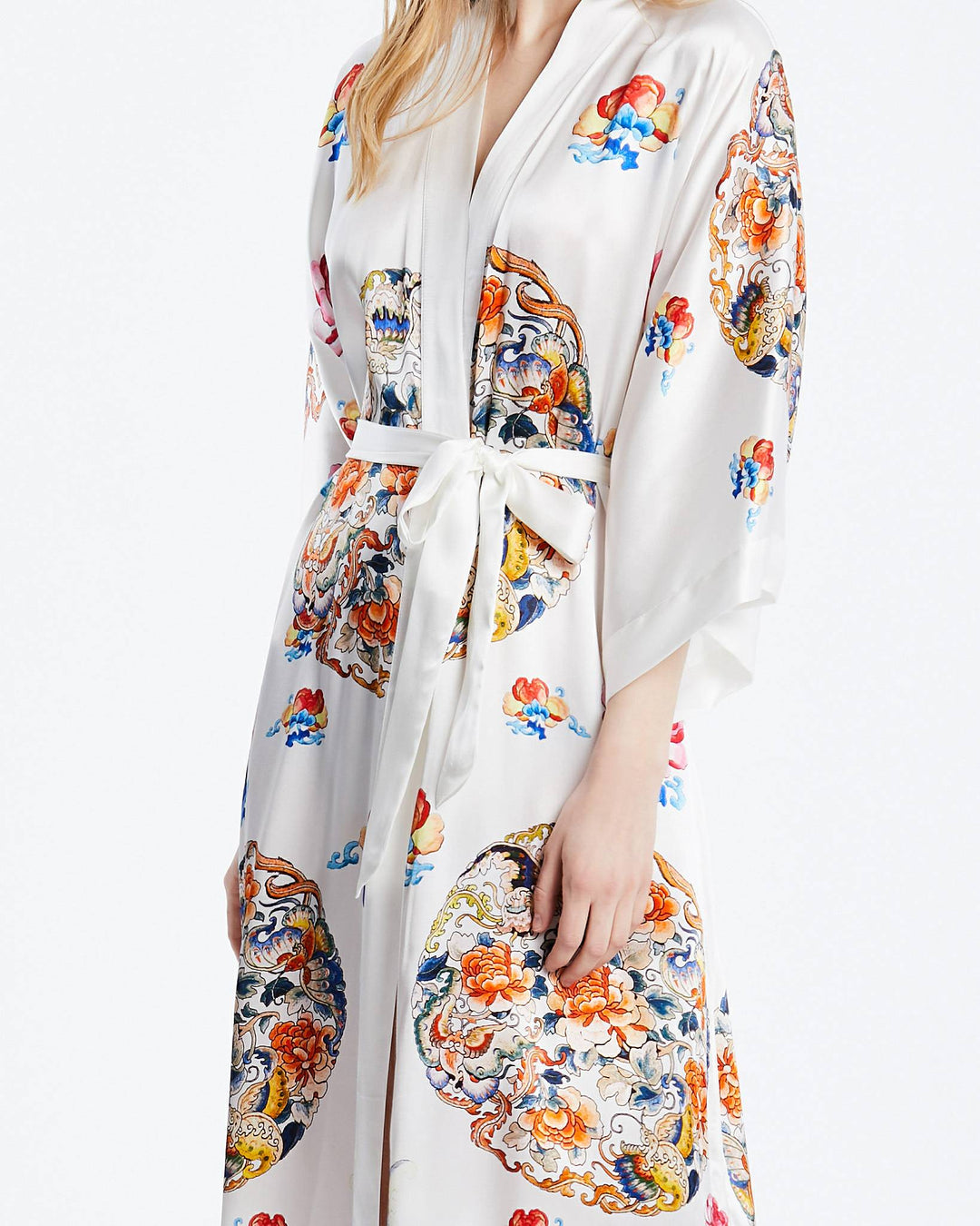 A person wearing the exquisite SusanSilk "Wheel of Fortune" long silk kimono, adorned with colorful and intricate floral patterns, and elegantly tied at the waist with a sash.#color_white