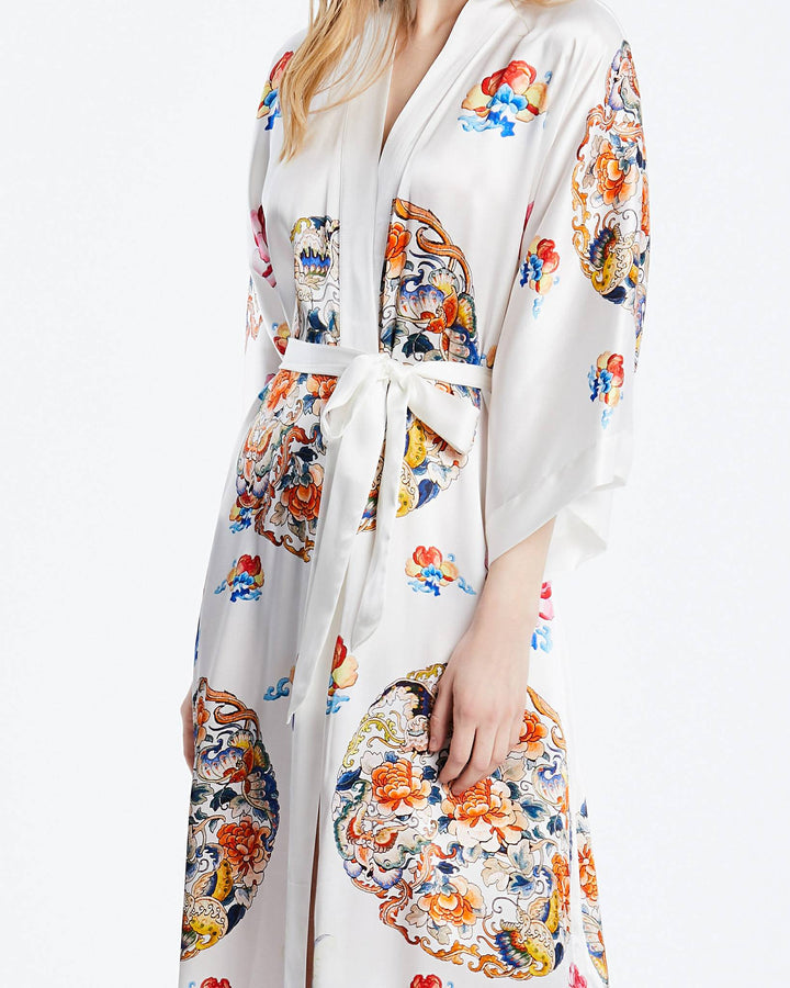 A person wearing the exquisite SusanSilk "Wheel of Fortune" long silk kimono, adorned with colorful and intricate floral patterns, and elegantly tied at the waist with a sash.#color_white