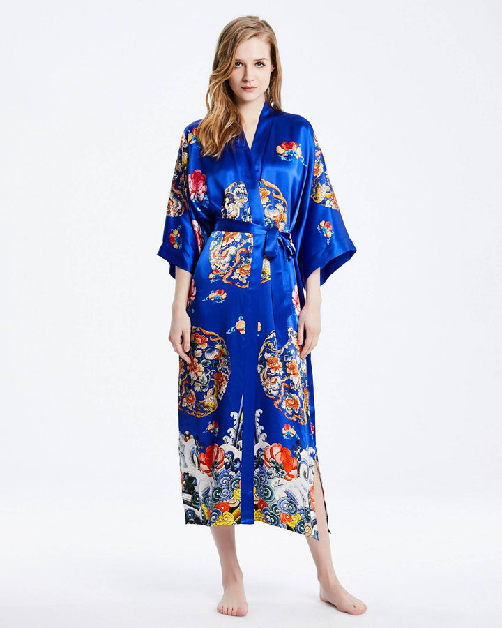 A person stands barefoot, wearing a Wheel of Fortune Long Silk Kimono from SusanSilk, adorned with vibrant, colorful designs.#color_royal-blue