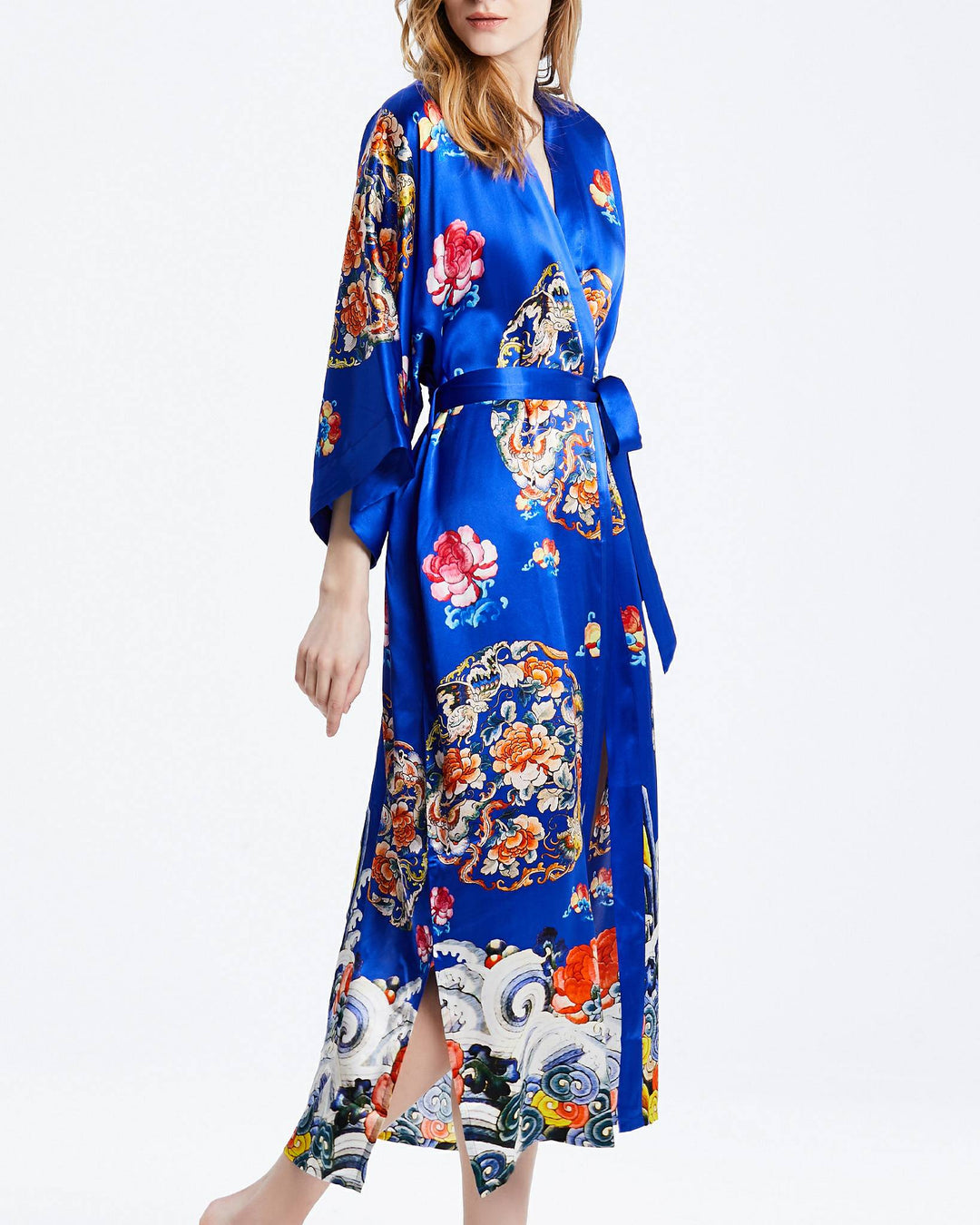 A person wears the Wheel of Fortune Long Silk Kimono by SusanSilk, a beautiful blue garment adorned with floral and paisley patterns, featuring a tie belt and side slits.#color_royal-blue