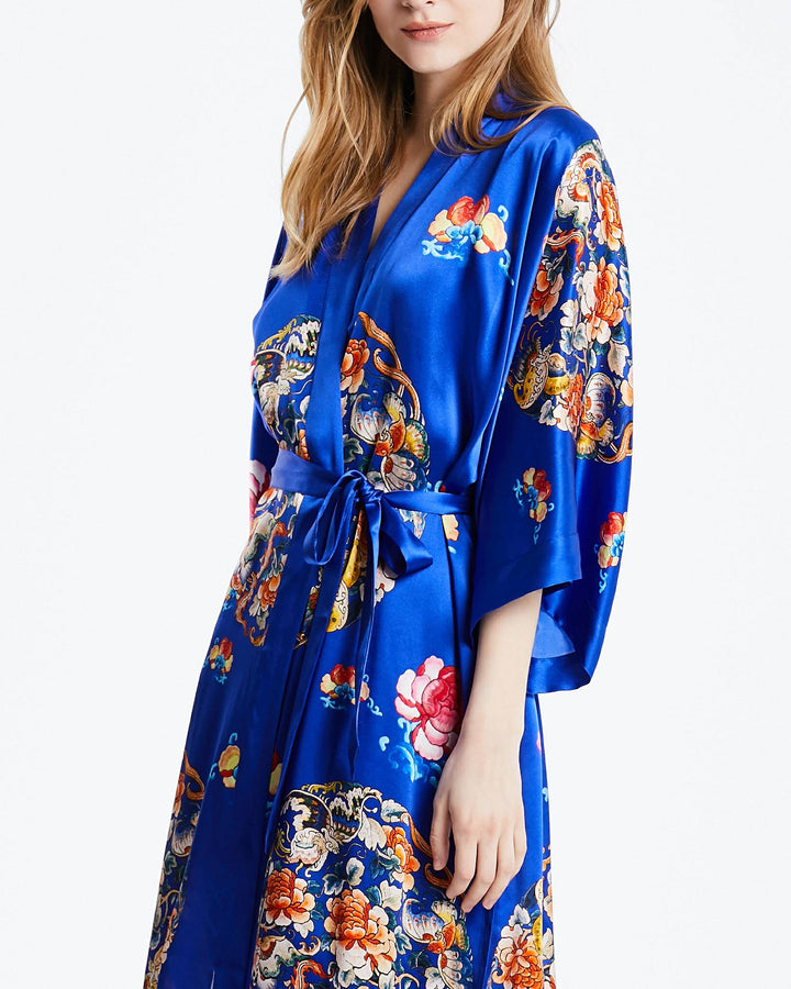 A person wearing a Wheel of Fortune Long Silk Kimono with wide sleeves and a tied waist belt by SusanSilk.#color_royal-blue