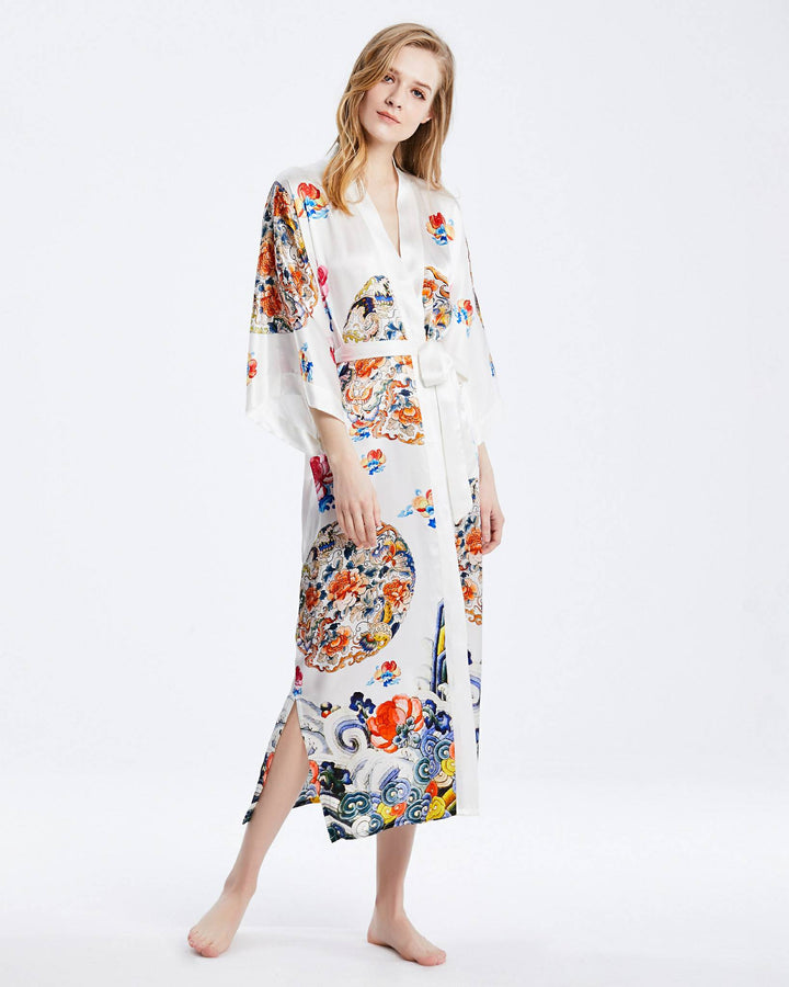 A person stands barefoot wearing the Wheel of Fortune Long Silk Kimono by SusanSilk, adorned with colorful patterns.#color_white