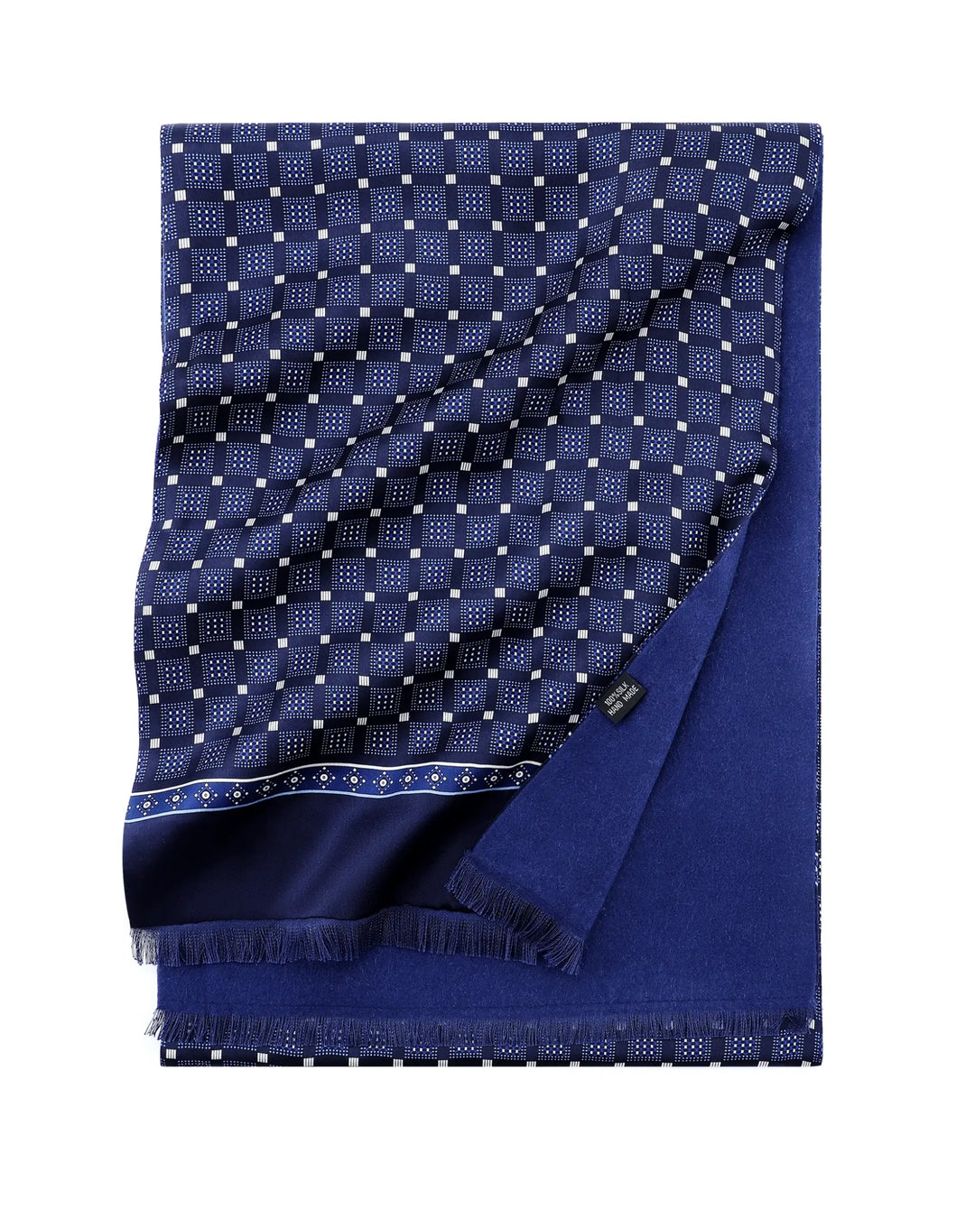 A folded navy blue scarf with a white geometric checkered pattern on one side and solid navy blue fringe on the other, displayed on a clean white background.#color_navy-blue
