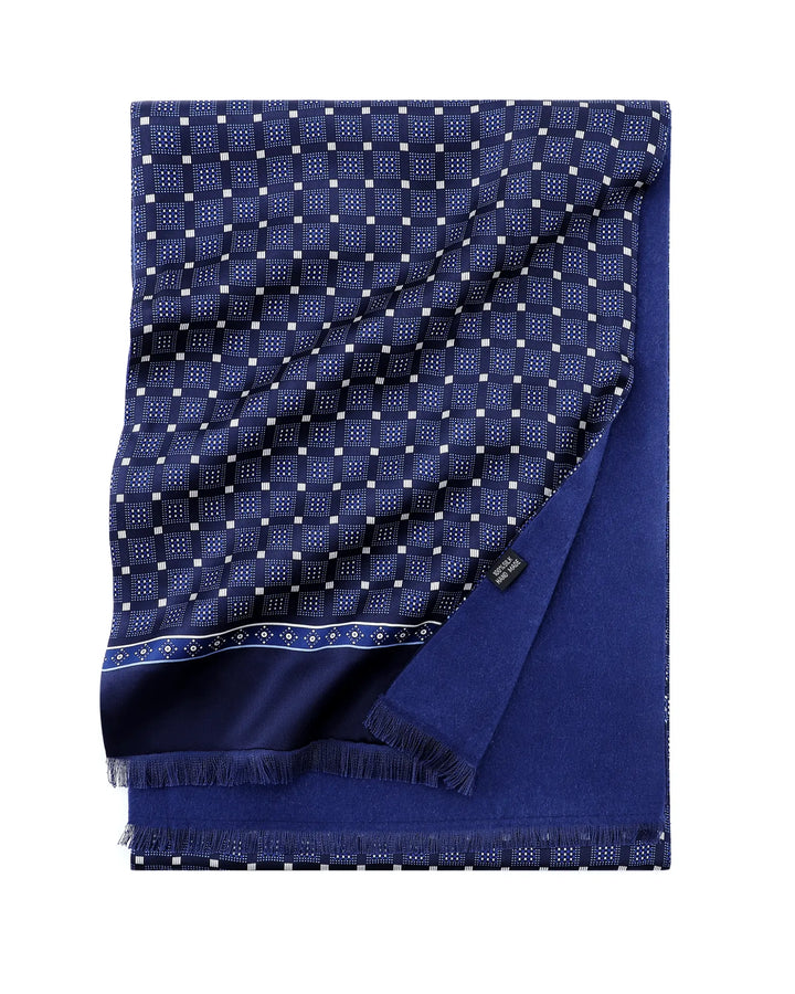 A folded navy blue scarf with a white geometric checkered pattern on one side and solid navy blue fringe on the other, displayed on a clean white background.#color_navy-blue