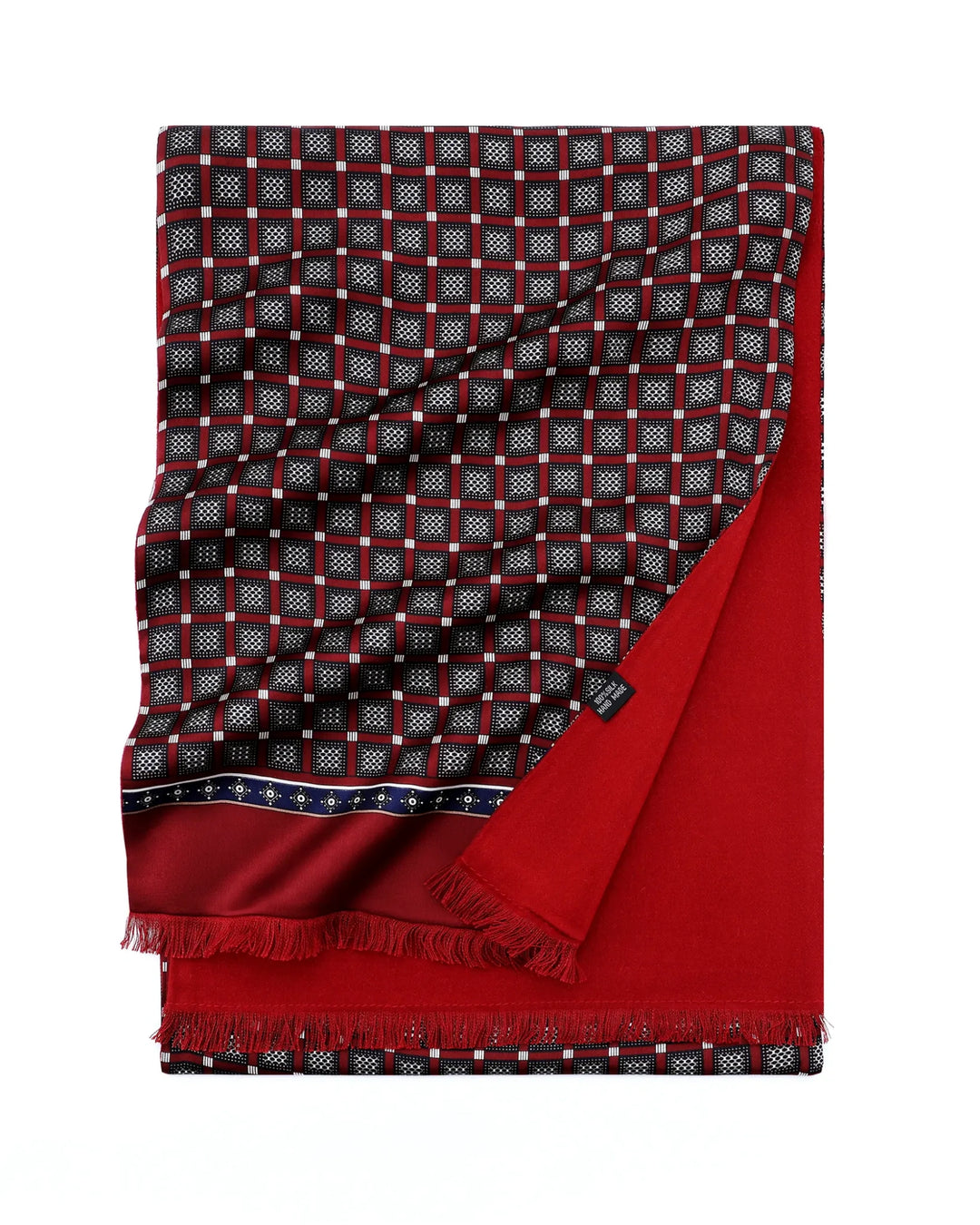 A folded red and black patterned scarf with white geometric details, featuring a solid red reverse side and fringed edges, shown on a plain white background.#color_wine-red