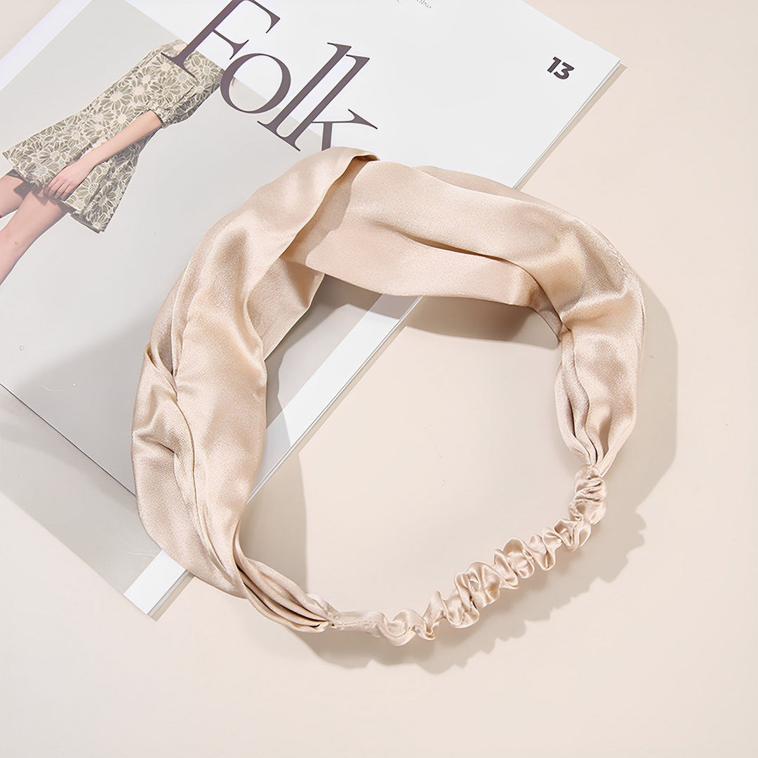 A Pure Color Criss Cross Silk Headband from SusanSilk graces the pages of a fashion magazine, complementing a model in an elegant dress.