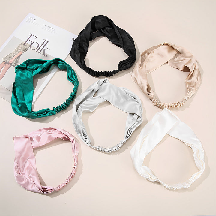 Six SusanSilk Pure Color Criss Cross Silk Headbands—available in black, beige, emerald, silver, light pink, and white—are arranged in a semicircle on a white surface next to a magazine titled "Folk.