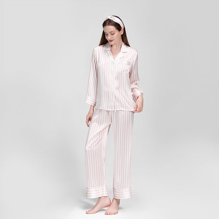 A woman wearing SusanSilk's 19 Momme Chic Stripe Silk Pajamas Set and a matching headband stands barefoot against a plain white background.
