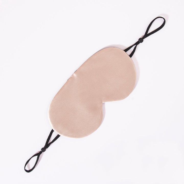 An Earth Tones Double Side Silk Eye Mask by SusanSilk, featuring light beige fabric and black adjustable elastic straps, is displayed against a white background.