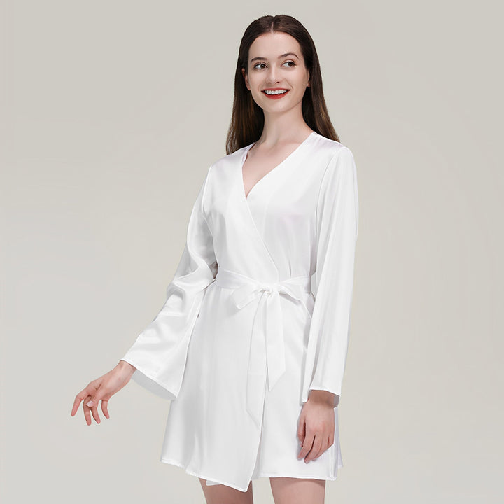 A person with long, flowing hair wearing the 19 Momme Mid Length Silk Robe by SusanSilk is smiling, standing against a plain background.