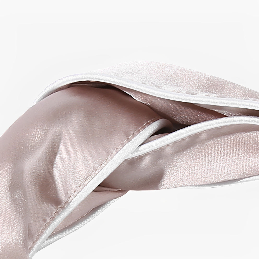 Close-up of the SusanSilk Piping Criss Cross Silk Headband in light pink, neatly folded with a slight sheen, resting against a plain white background.