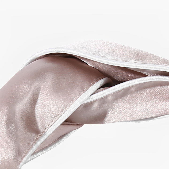 Close-up of the SusanSilk Piping Criss Cross Silk Headband in light pink, neatly folded with a slight sheen, resting against a plain white background.