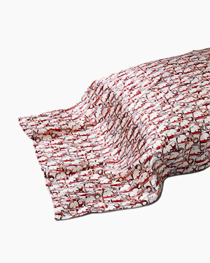 The 19 Momme Printing Silk Pillow Cover from SusanSilk showcases a luxurious silk fabric adorned with an exquisite red and white pattern of interlocking loops, beautifully draped to highlight its elegant folds and creases.