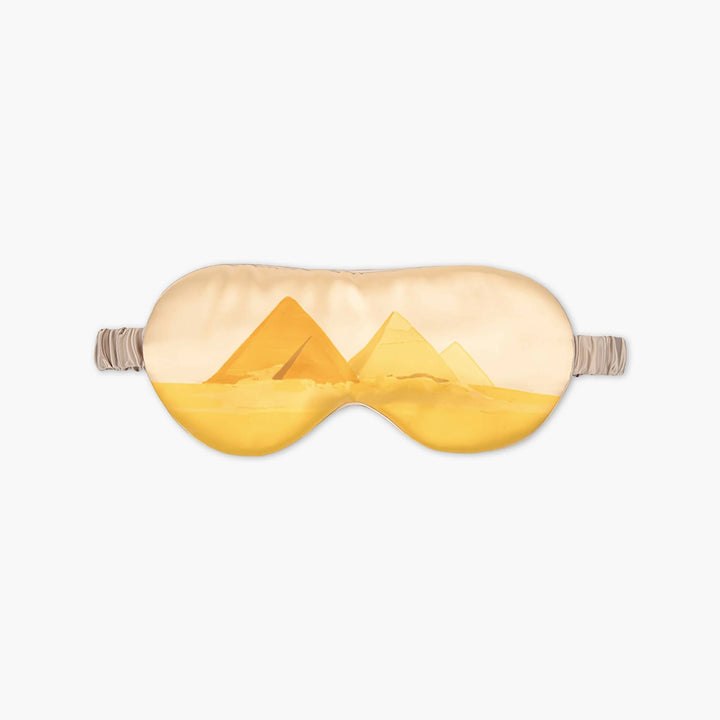 An Elegant Silk Eye Mask - Golden Pyramid by SusanSilk featuring an illustration of the Egyptian pyramids in a desert setting.