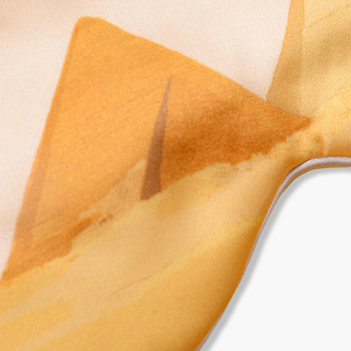 Close-up image of an Elegant Silk Eye Mask - Golden Pyramid by SusanSilk, featuring a printed design of yellow and orange triangular shapes.