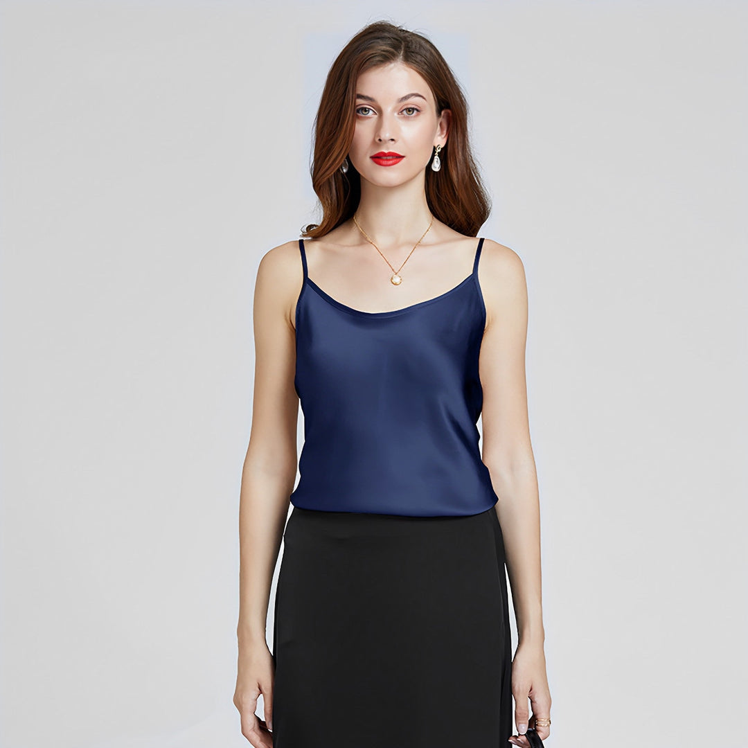 A woman with long brown hair wearing the Classic Round Neck Silk Camisole by SusanSilk in navy blue and a black skirt stands against a plain background.