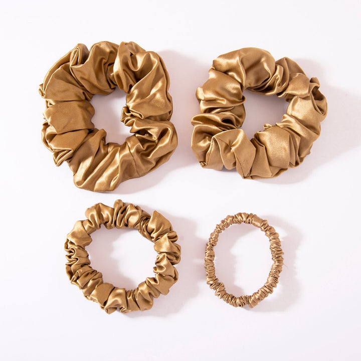 Four scrunchies from the 22 Momme Luxury Silk Scrunchies Set 4-Pack by SusanSilk, all gold-colored and of varying sizes, are arranged on a white background.