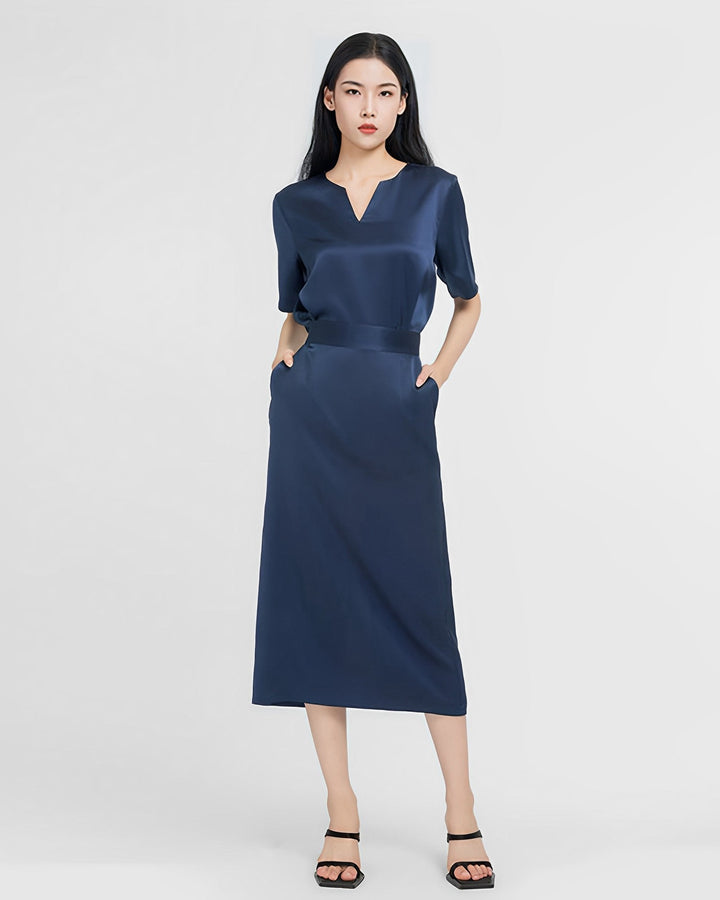 A person wearing an Elegant Two-Piece Silk Dress Set by SusanSilk in navy blue and black sandals stands against a plain white background with hands in pockets.