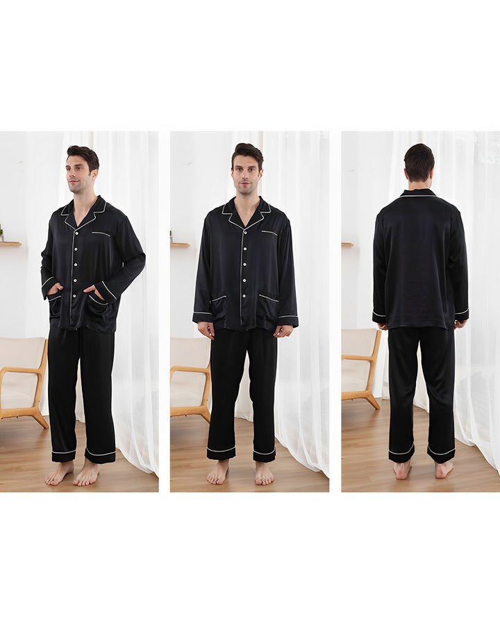 A man models the 25 Momme Lapel Collar Silk Pajama Set from SusanSilk, featuring a black design with white trim. The image showcases front, side, and back views. He is standing on a wooden floor in a room adorned with white curtains and wooden furniture.