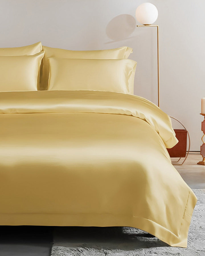 A serene atmosphere is created in a tidy bedroom featuring a yellow 25 Momme Seamless Luxury Duvet Cover with matching pillows, beautifully illuminated by a floor lamp with a spherical shade. The SusanSilk texture of the duvet cover adds an element of luxury and sophistication.