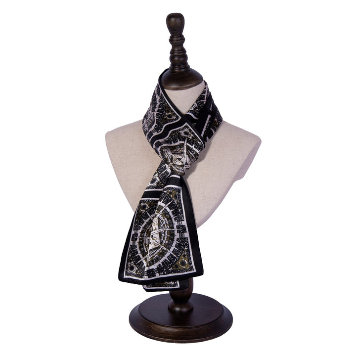 A Black Compass Narrow Long Silk Scarf by SusanSilk, featuring a black and white pattern, displayed on a mannequin bust with a wooden base.