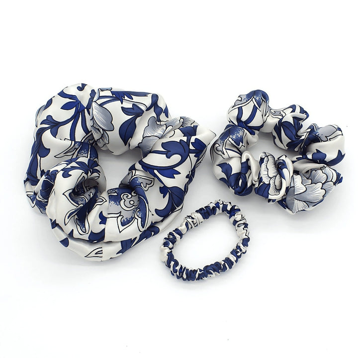Three elastic hair scrunchies from the SusanSilk Celadon Print Silk Scrunchies Set 3-Pack, featuring luxurious silk with white and blue floral patterns, are arranged against a white background.