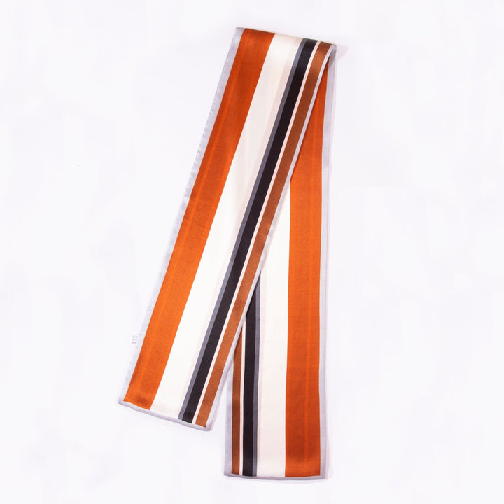 A luxurious Color Strips Narrow Long Silk Scarf by SusanSilk, featuring vertical stripes in orange, black, white, and beige.