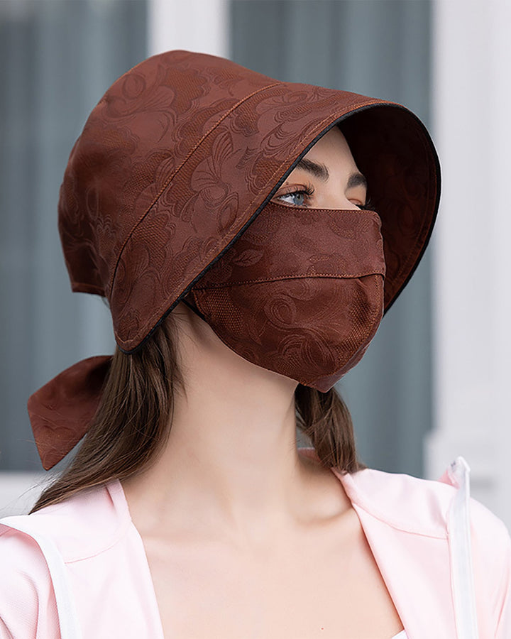 Person wearing a Jacquard Cloche Hat & Face Mask by SusanSilk, looking to the side. They have long hair tied back and are wearing a light-colored top made of susansilk.