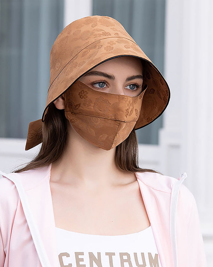 A woman wearing the Jacquard Cloche Hat & Face Mask by SusanSilk stands in front of a light-colored background. She is dressed in an elegant, light pink jacket over a white top, reminiscent of SusanSilk's refined aesthetic.