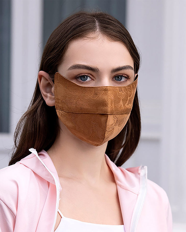 A woman with long brown hair, wearing a Jacquard Large Brim Hat & Face Mask by SusanSilk and a light pink jacket, looks directly at the camera.