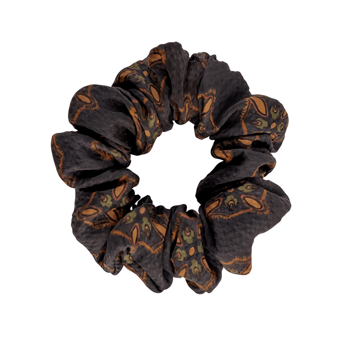A Gambiered Canton Gauze Silk Scrunchie from SusanSilk, featuring a pattern of brown and green animal faces.