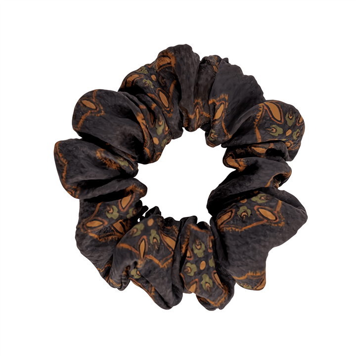 A Gambiered Canton Gauze Silk Scrunchie from SusanSilk, featuring a pattern of brown and green animal faces.