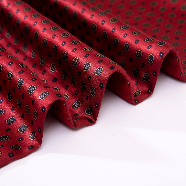 A close-up image of the folded Geometric Pattern Long Silk Brushed Scarf - Garnet by SusanSilk, showcasing its subtle black and gold geometric design.