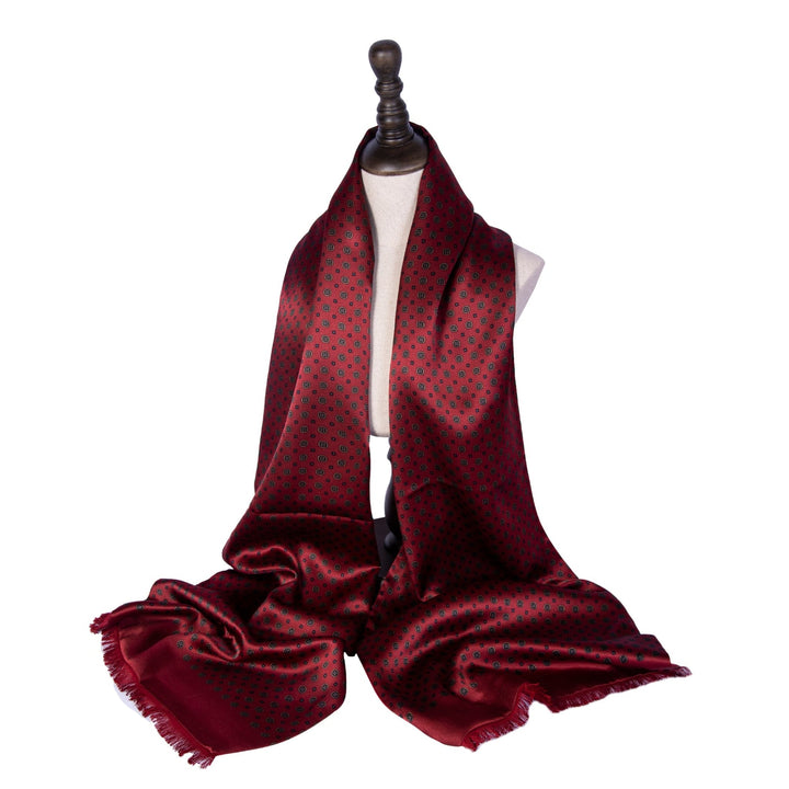 A Geometric Pattern Long Silk Brushed Scarf in Garnet by SusanSilk is draped over a mannequin bust, showcasing its small black patterns against a white background.