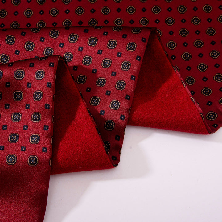 Close-up of a folded Geometric Pattern Long Silk Brushed Scarf - Garnet by SusanSilk, showcasing a black and white geometric pattern. The scarf features small hexagonal shapes and is partially unfolded on a white surface.