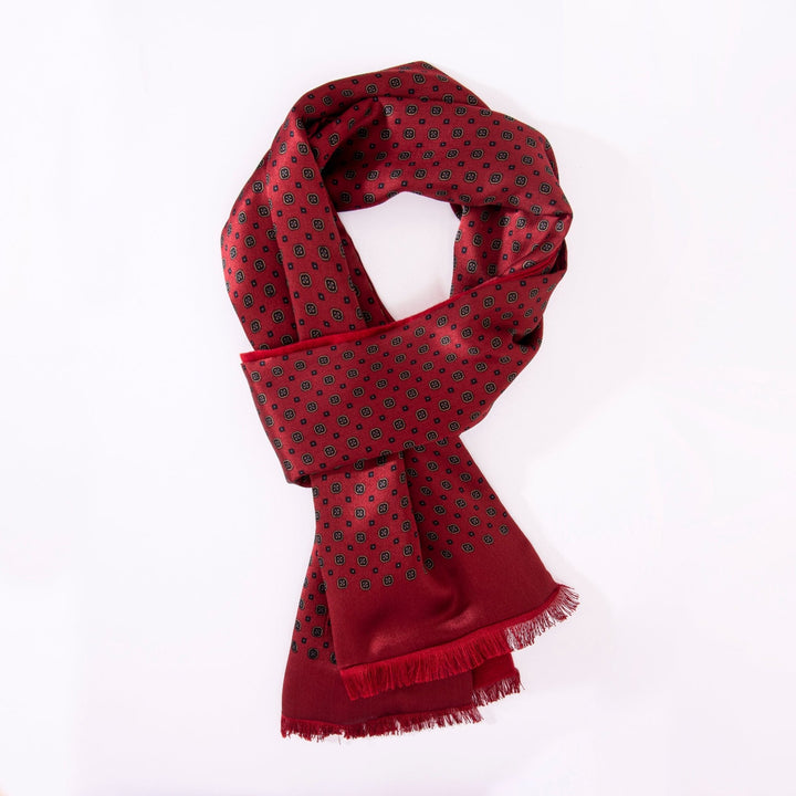 A SusanSilk Geometric Pattern Long Silk Brushed Scarf in Garnet, featuring small black squares and fringed ends, gracefully arranged in a loop on a plain white background.