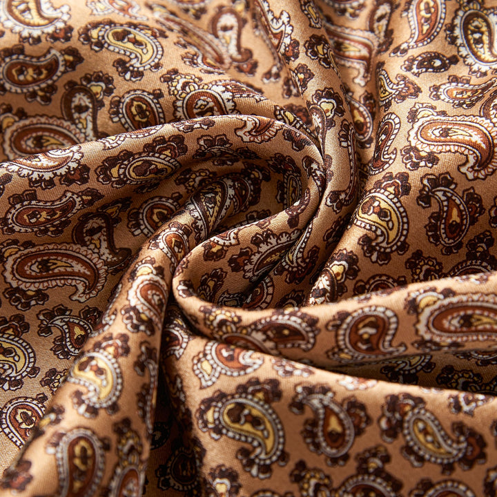 Close-up of the Paisley Long Silk Brushed Scarf in Gold by SusanSilk, with the brown paisley-patterned material gathered in the center.