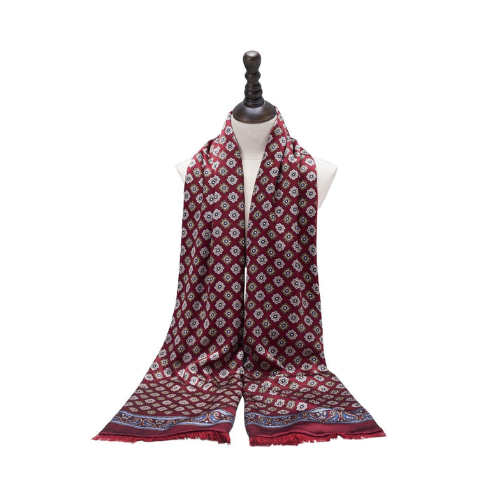 A red geometric pattern long silk brushed scarf by SusanSilk, featuring white motifs and a colorful border, displayed on a mannequin bust.