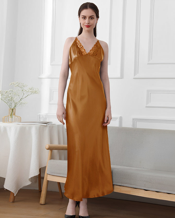 A woman stands in a room wearing the elegant Lace Long Silk Nightdress by SusanSilk. She stands in front of a bench, and a table with flowers is visible in the background.