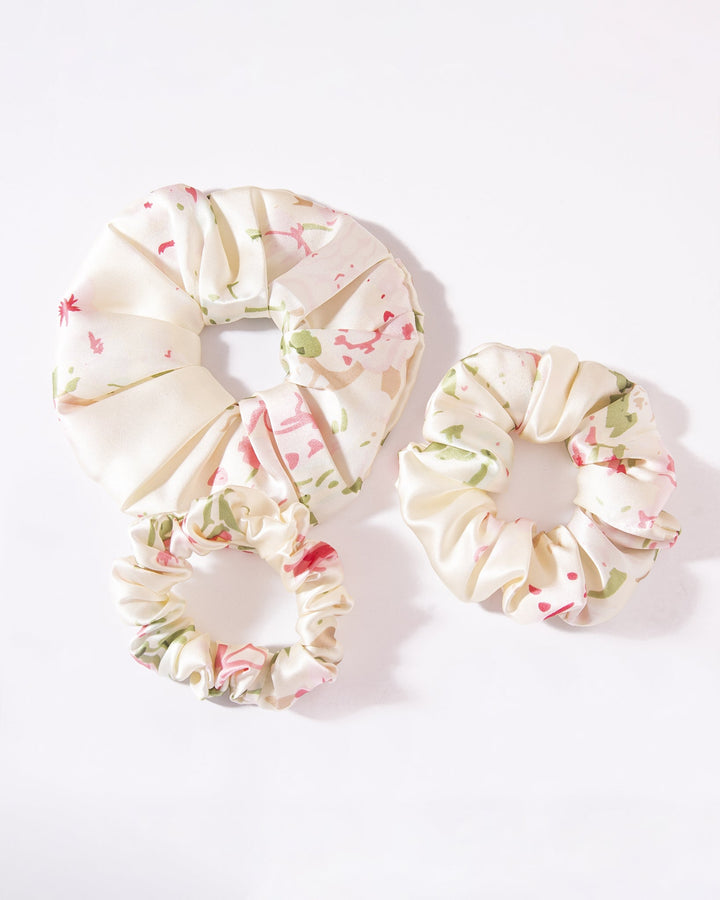 Three Lovely Flowers Silk Scrunchies from SusanSilk, featuring varying sizes and an elegant white floral pattern, are beautifully displayed on a pristine white background.