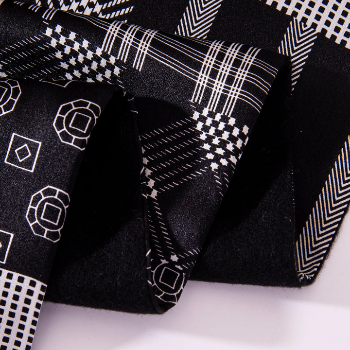 A folded SusanSilk Mix Pattern Long Silk Brushed Scarf showcasing its black fabric with white geometric patterns, including squares, diamonds, and circles.