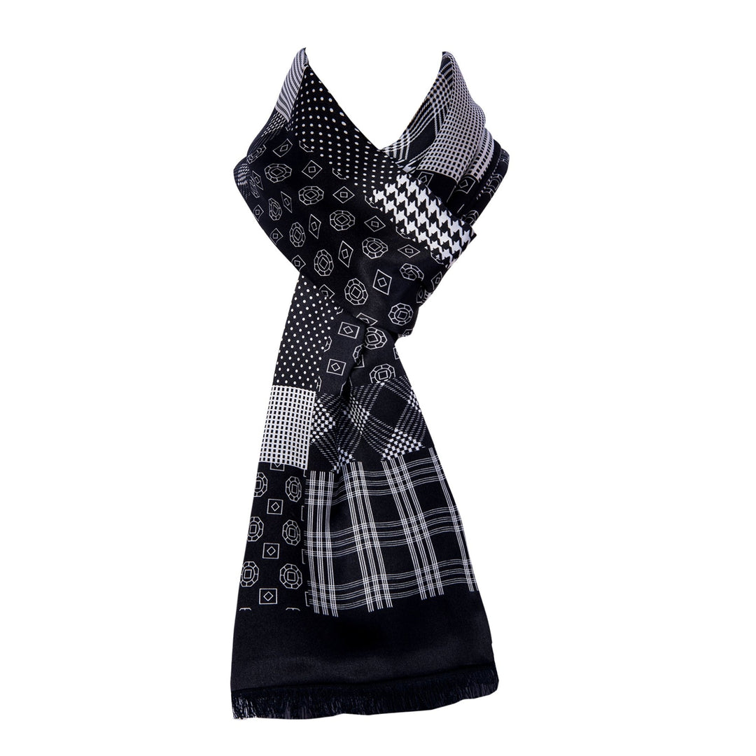 The Mix Pattern Long Silk Brushed Scarf by SusanSilk, featuring an array of geometric patterns such as checks, dots, and cubes in black and white, is elegantly displayed upright against a plain white background.