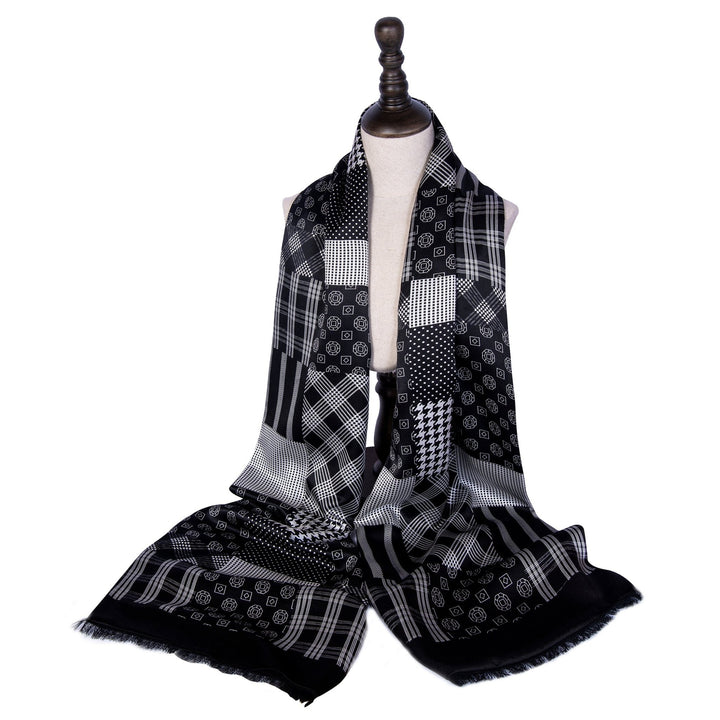 A Mix Pattern Long Silk Brushed Scarf by SusanSilk is draped over a mannequin. The luxurious black and white scarf features various geometric designs, including squares and stripes.