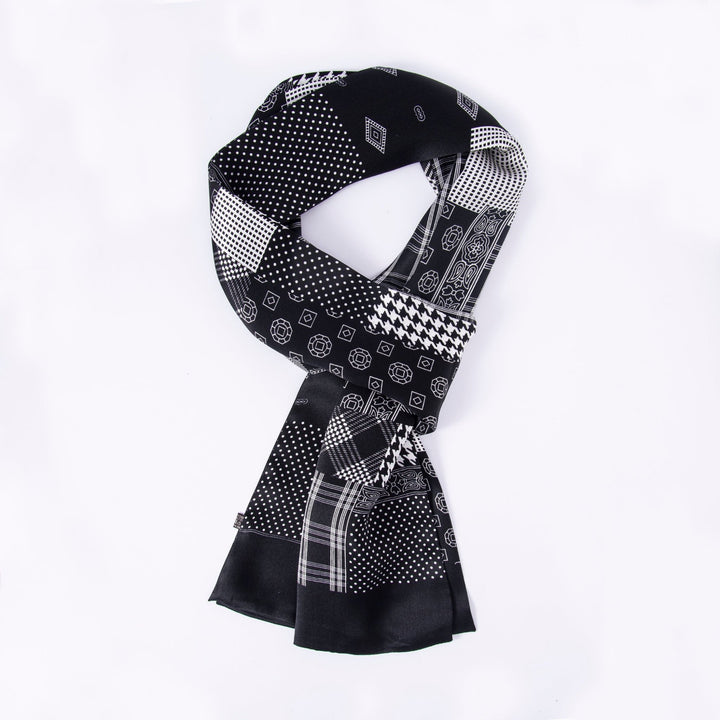 A SusanSilk Mix Pattern Long Silk Scarf, featuring an array of black and white geometric designs—including polka dots, squares, and rectangles—arranged in an intricate patchwork against a plain white background.