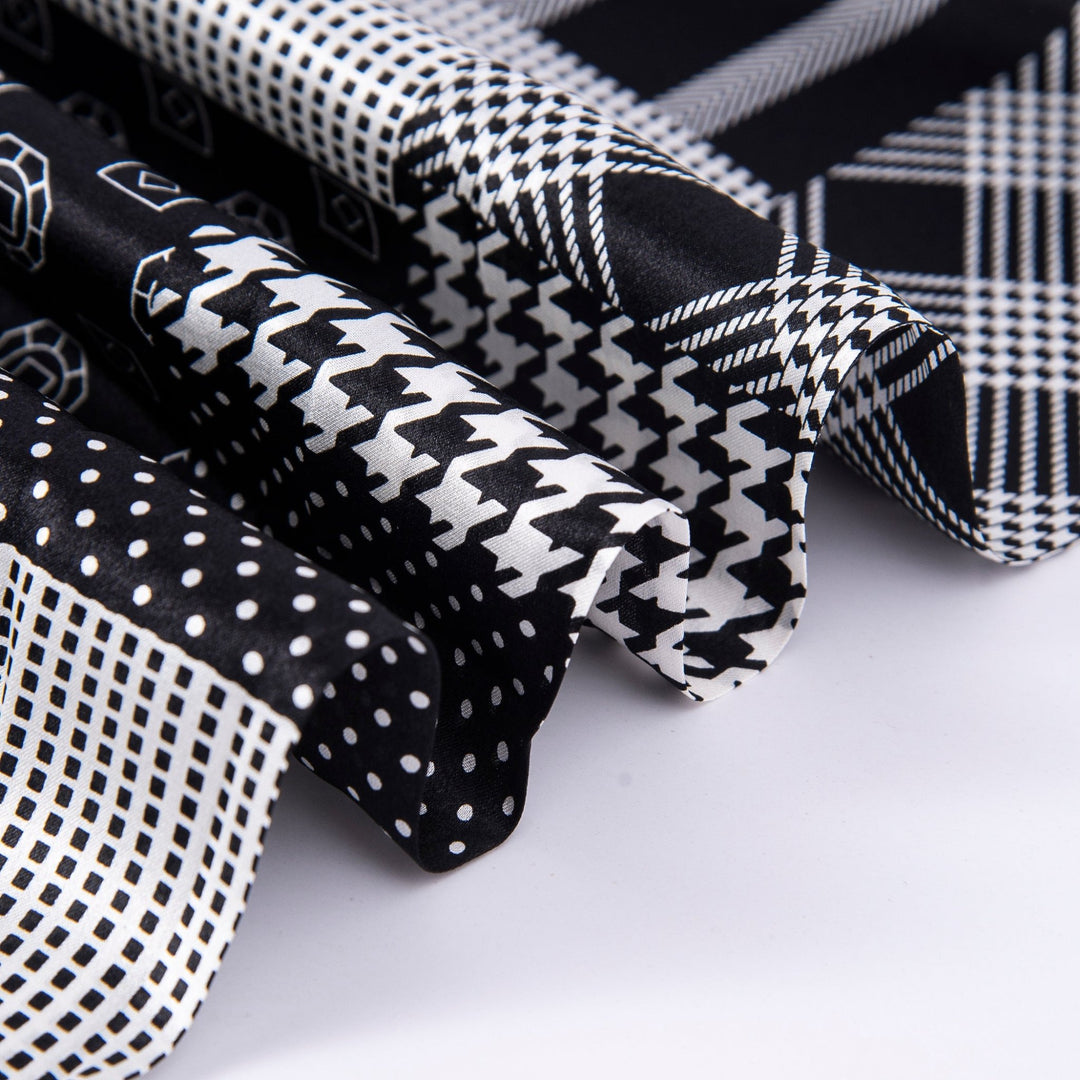 Close-up of various black and white fabric swatches, including polka dots, houndstooth, geometric shapes, and plaid. Some of the swatches feature luxurious SusanSilk's Mix Pattern Long Silk Scarf for an elegant touch.