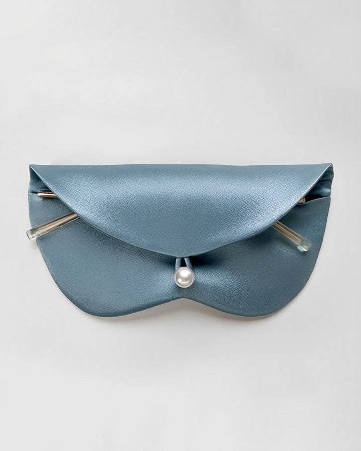 A sleek light blue glasses pouch with a semi-circular front flap, metal accents, and a pearl-like button clasp, crafted from luxurious SusanSilk fabric.