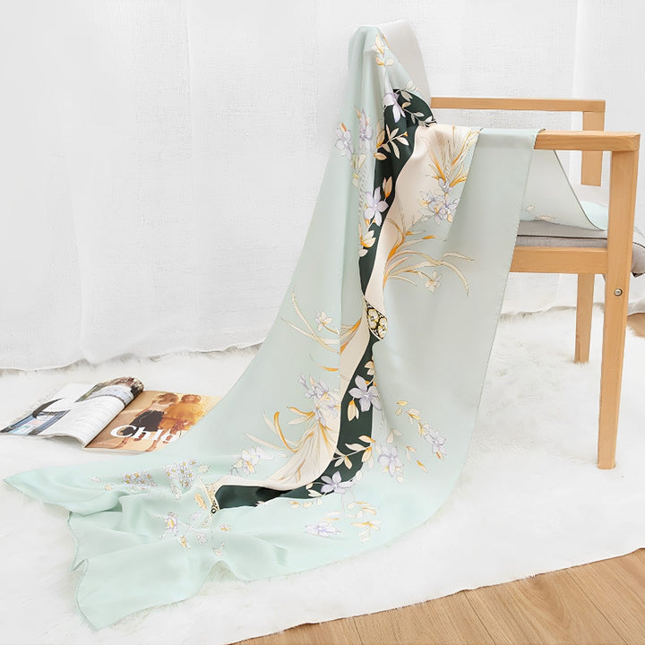 An Ornament & Floral Long Silk Crepe Scarf by SusanSilk draped over a wooden chair, next to an open magazine on a white fur rug.