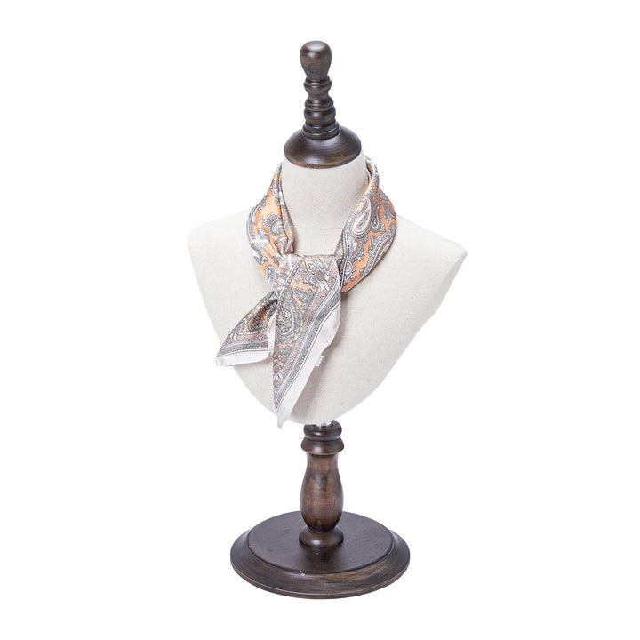 A Paisley Series Square Silk Scarf by SusanSilk is displayed on a bust mannequin with a dark wooden stand.